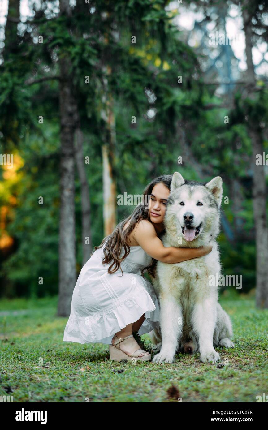 Une jeune femme atteinte de désordre inné nanisme embrasse le chien malamute tout en marchant dans le parc. Banque D'Images