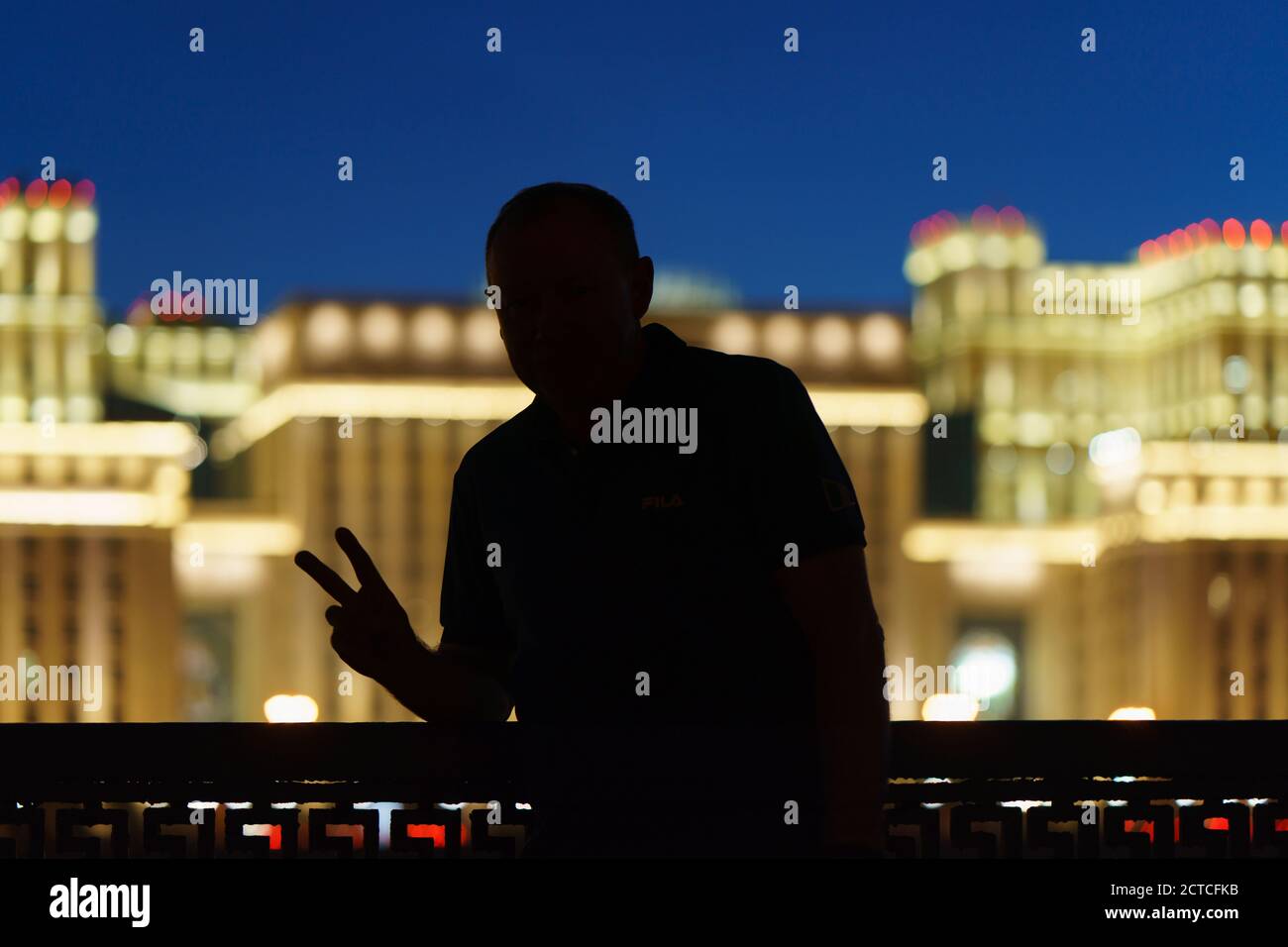 Silhouette d'un homme. Langue des signes. Signe V. L'utilisation la plus répandue comme signe de victoire (V pour victoire). Paysage urbain de Moscou avec architecture stalinienne Banque D'Images