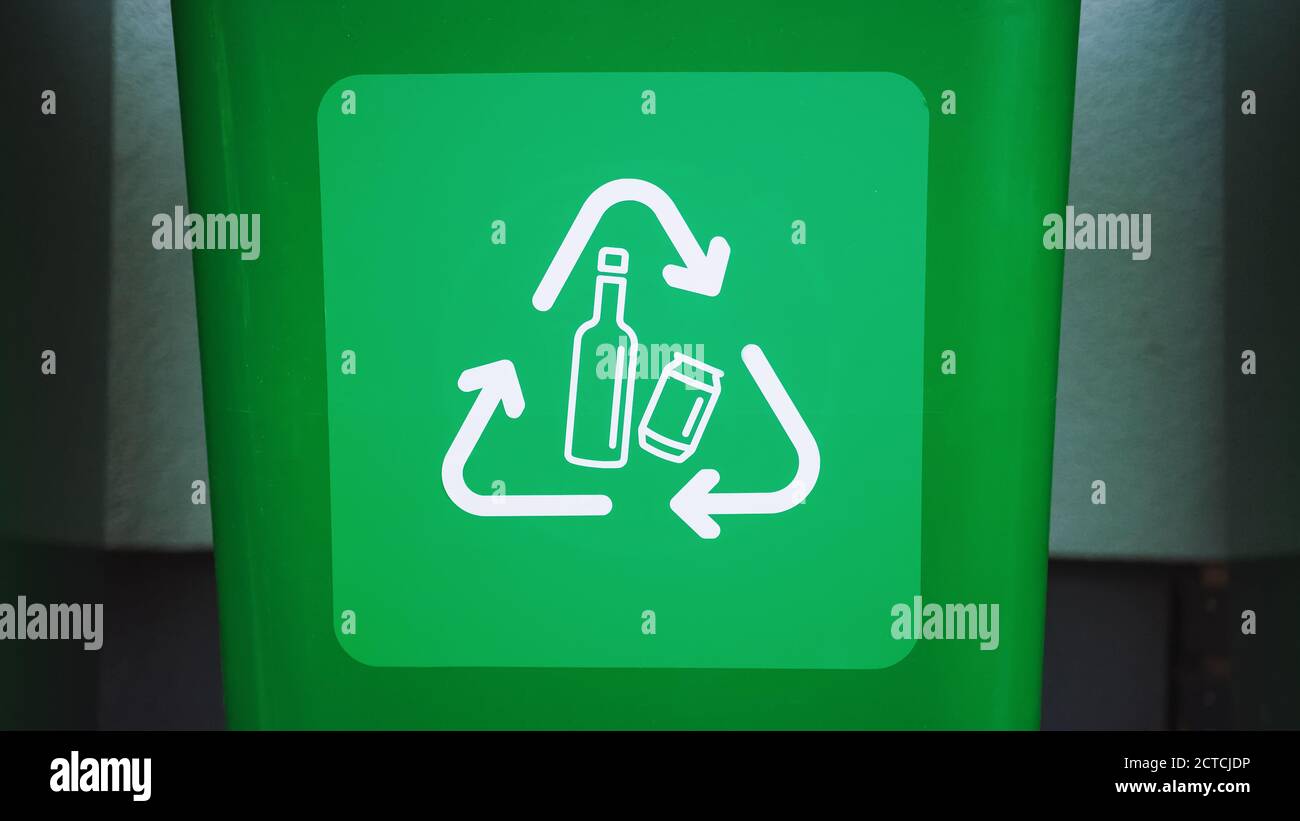 Gros plan une poubelle en plastique de couleur verte, avec logos de recyclage des bouteilles à l'avant. Concept de tri des déchets pour les bouteilles. Enregistrement de l'environnement Banque D'Images