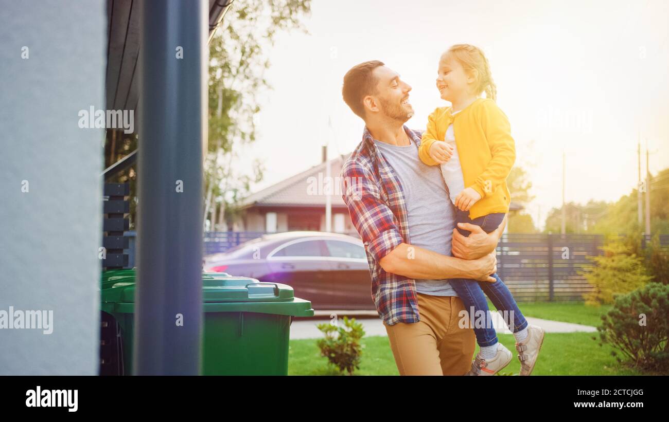 Père heureux tenant une jeune fille. Ils ont jeté les déchets dans les poubelles appropriées parce que cette famille est en train de trier les déchets et d'aider l'environnement Banque D'Images