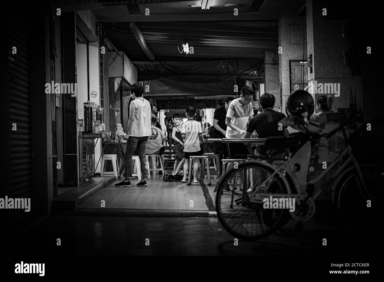 Les enfants jouent devant un stand de restauration dans la salle de jeux de Tainan Street. Voir et sourire vers l'appareil photo. Banque D'Images