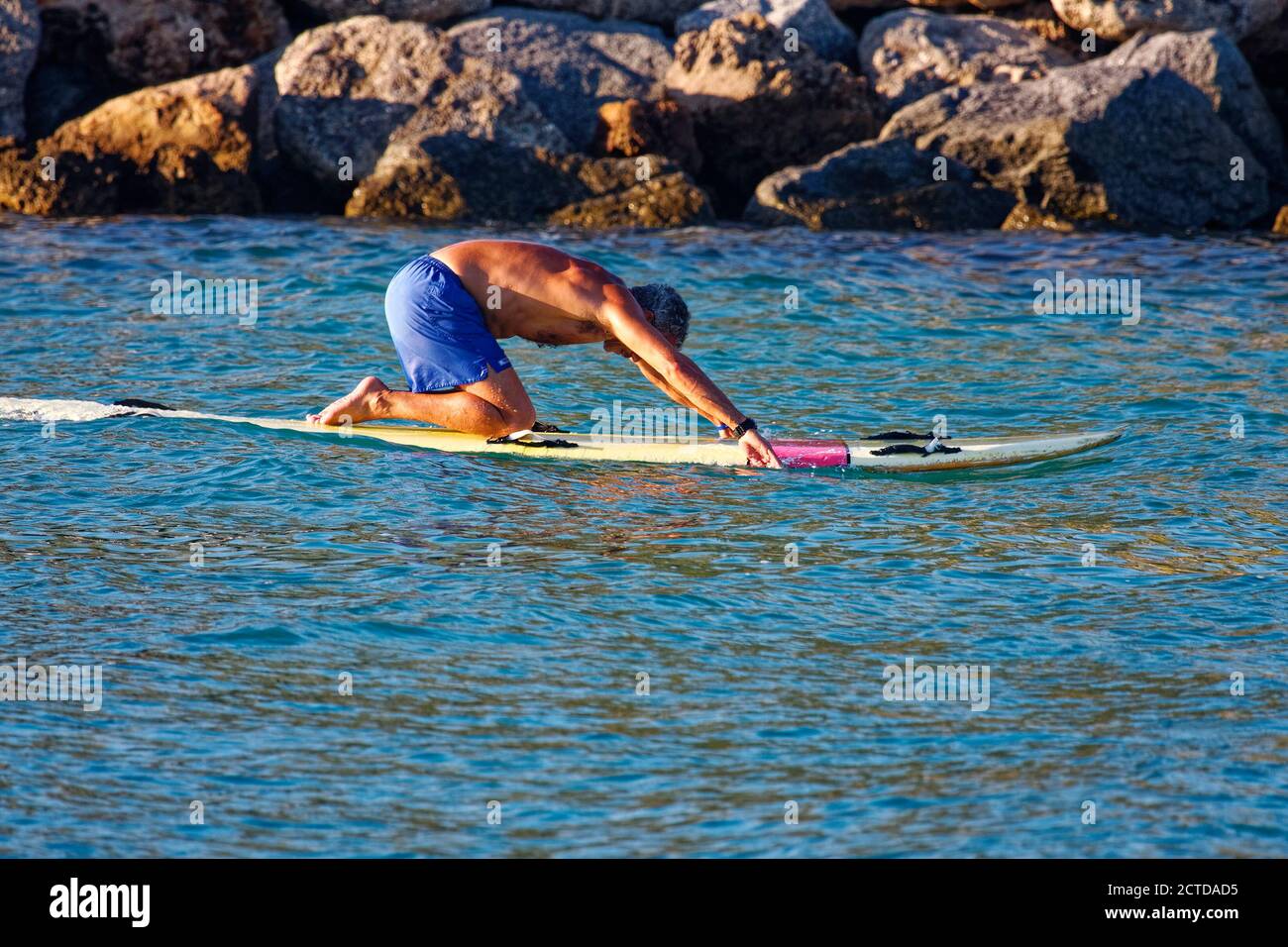 Homme pagayer main planche de surf; agenouiller; sport; exercice, fatigante, activité physique, passant la jetée de roche, Venice Inlet; Floride, Venise; FL Banque D'Images