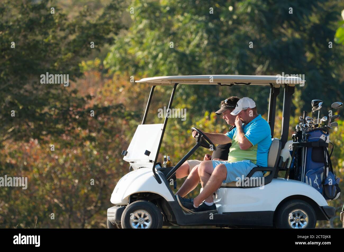 deux hommes et golfeurs de race blanche conduisent une voiturette de golf Une journée ensoleillée en Afrique du Sud Banque D'Images