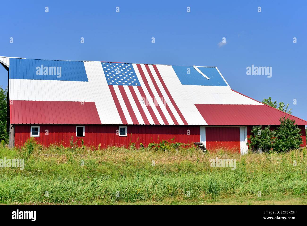 Sabula, Iowa, États-Unis. Une ancienne grange ancienne avec un toit rouge, blanc et bleu patriotique et un drapeau américain. Banque D'Images