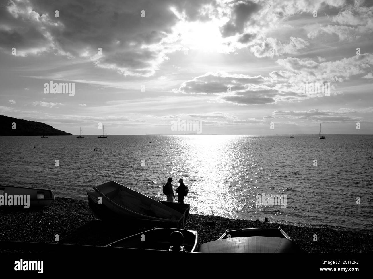 Un couple sur le front de mer de la plage de Totland Bay Isle of Le soir, le soleil couchant coucher de soleil derrière dans des yachts silhouette à ancrage dans la baie Banque D'Images