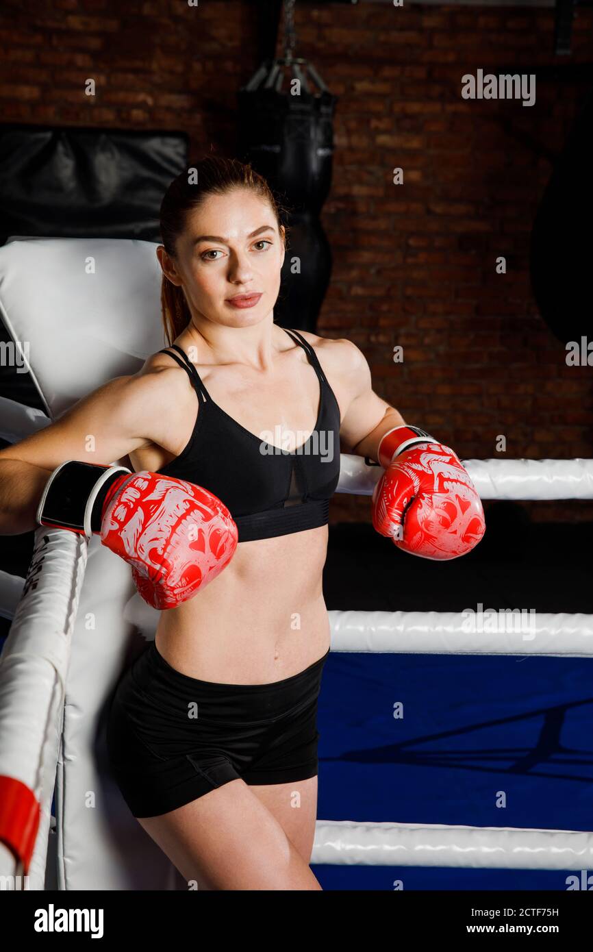 S adapte a la femme brune forte dans le haut de vetements de sport et le short dans les gants de boxe dans l anneau regarde la camera Photo Stock Alamy