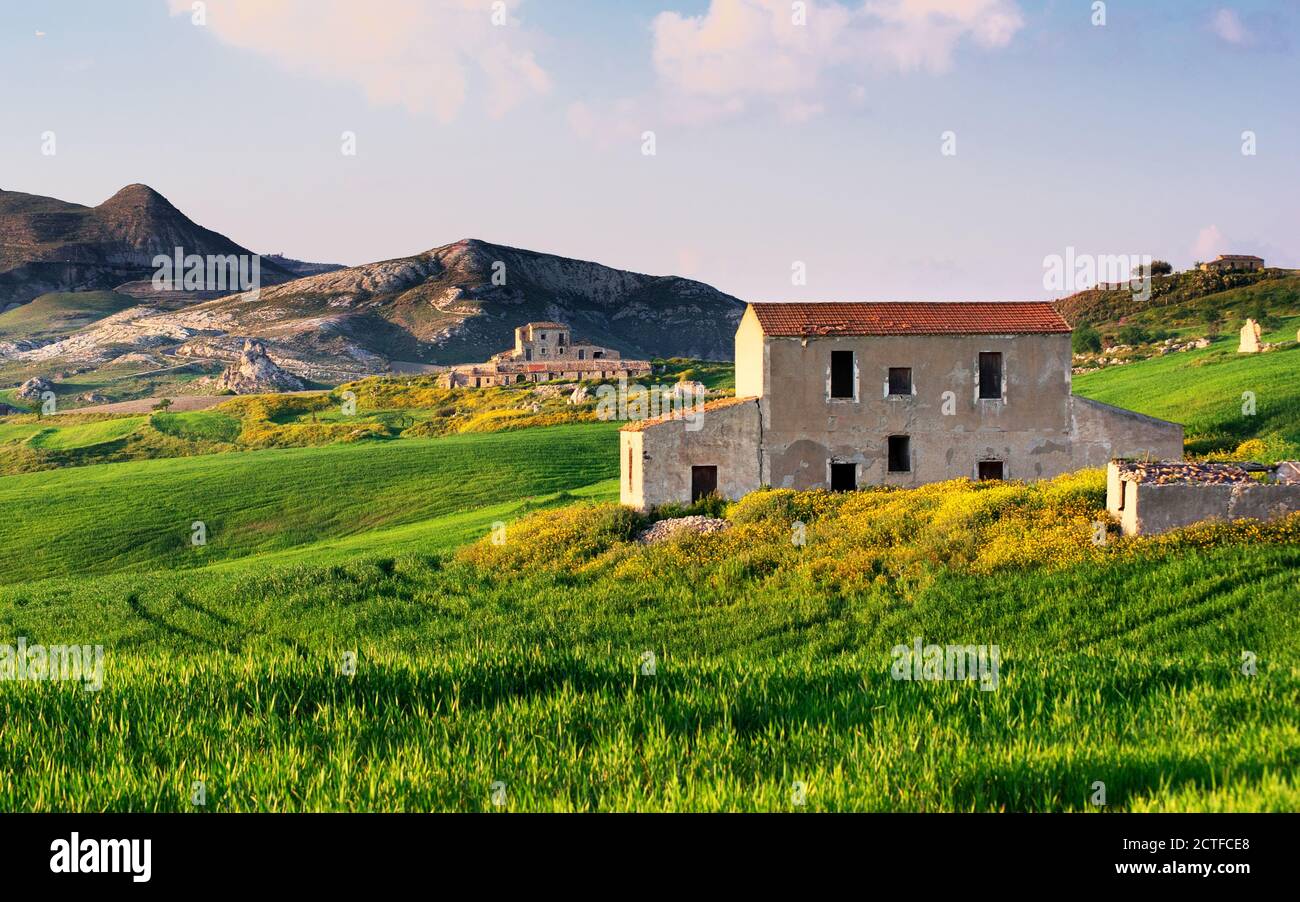 Paysage de Sicile reposant avec champs verts fleuris et ferme abandonnée maisons le soir Banque D'Images