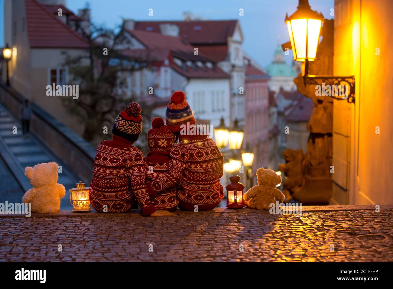 Beaux enfants, trois frères garçons, vêtus de façon décontractée, vue de nuit de Prague ville, l'hiver Banque D'Images