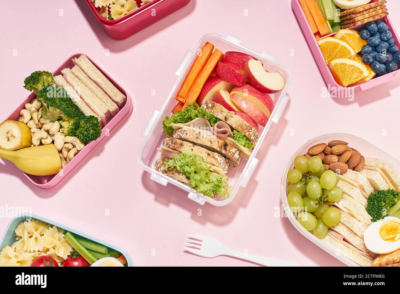 Vue de dessus avec des boîtes-repas scolaires avec divers repas sains nutritifs sur fond rose. Repas du midi d'en haut Banque D'Images