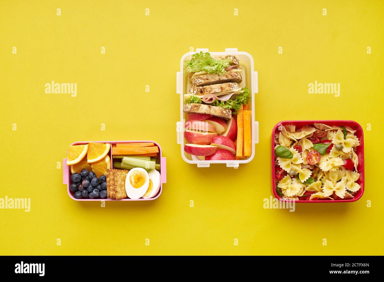 Vue de dessus des boîtes à lunch de l'école avec divers repas sains nutritifs sur fond jaune avec espace de copie Banque D'Images