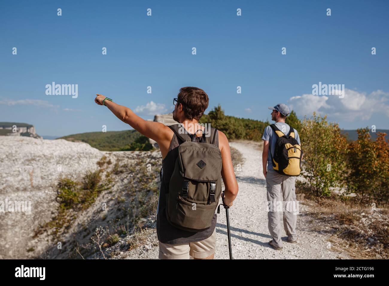 Deux randonneurs avec des sacs à dos et d'autres engins d'escalade restant au sommet du rocher. Homme pointant avec sa main discutant de la route. Plan, vision et mission concep Banque D'Images