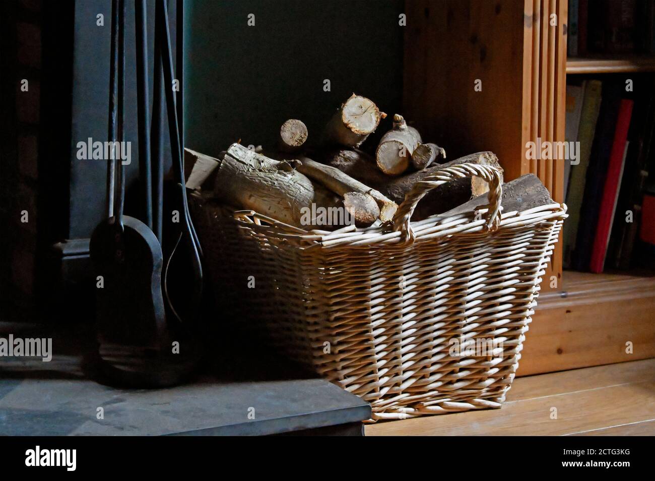 Les fers à feu et le bois de chauffage dans le panier sur le foyer. Banque D'Images