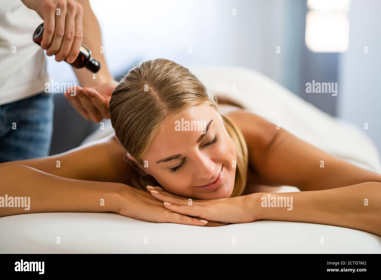 Masseur professionnel faisant un massage thérapeutique. Femme profitant d'un massage dans sa maison. Jeune femme se relaxant massage corporel. Banque D'Images