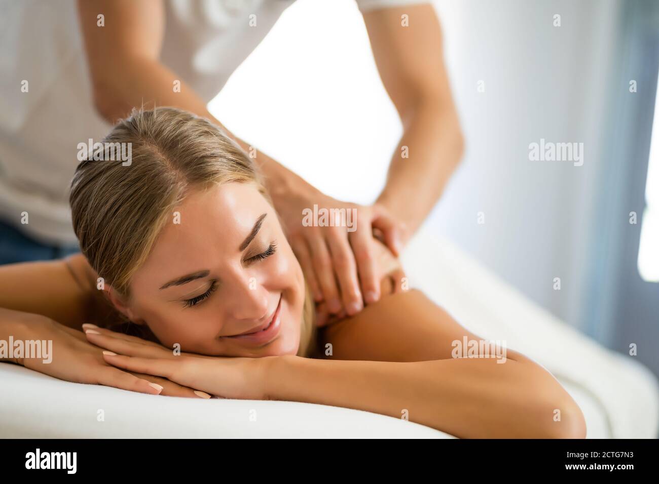 Masseur professionnel faisant un massage thérapeutique. Femme profitant d'un massage dans sa maison. Jeune femme se relaxant massage corporel. Banque D'Images