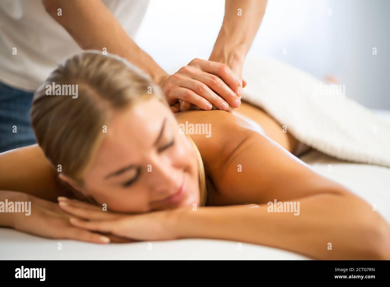 Masseur professionnel faisant un massage thérapeutique. Femme profitant d'un massage dans sa maison. Jeune femme se relaxant massage corporel. Banque D'Images