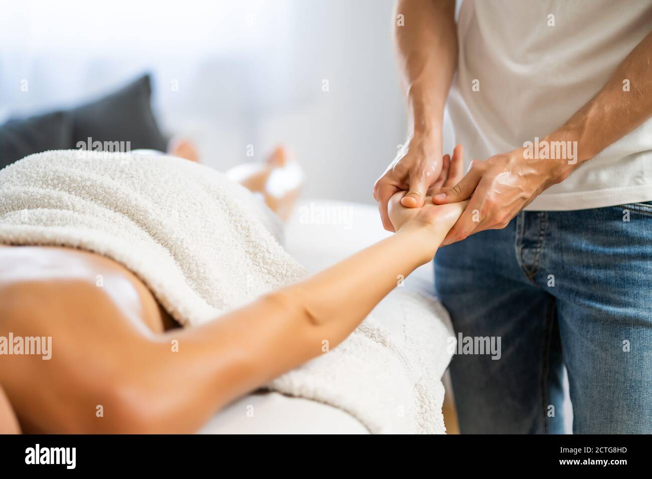 Masseur professionnel faisant un massage thérapeutique. Femme profitant d'un massage dans sa maison. Jeune femme se relaxant massage corporel. Banque D'Images