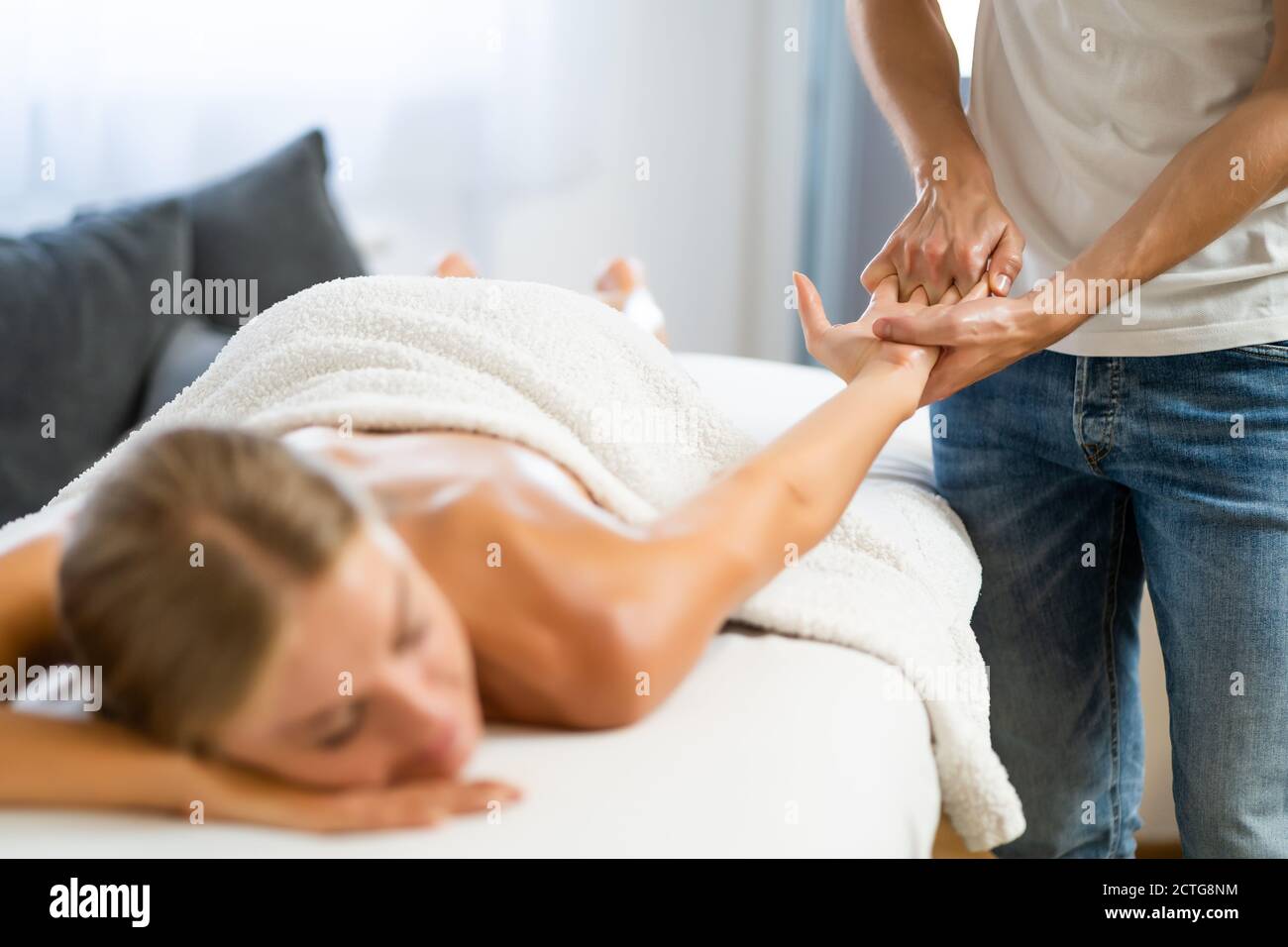 Masseur professionnel faisant un massage thérapeutique. Femme profitant d'un massage dans sa maison. Jeune femme se relaxant massage corporel. Banque D'Images