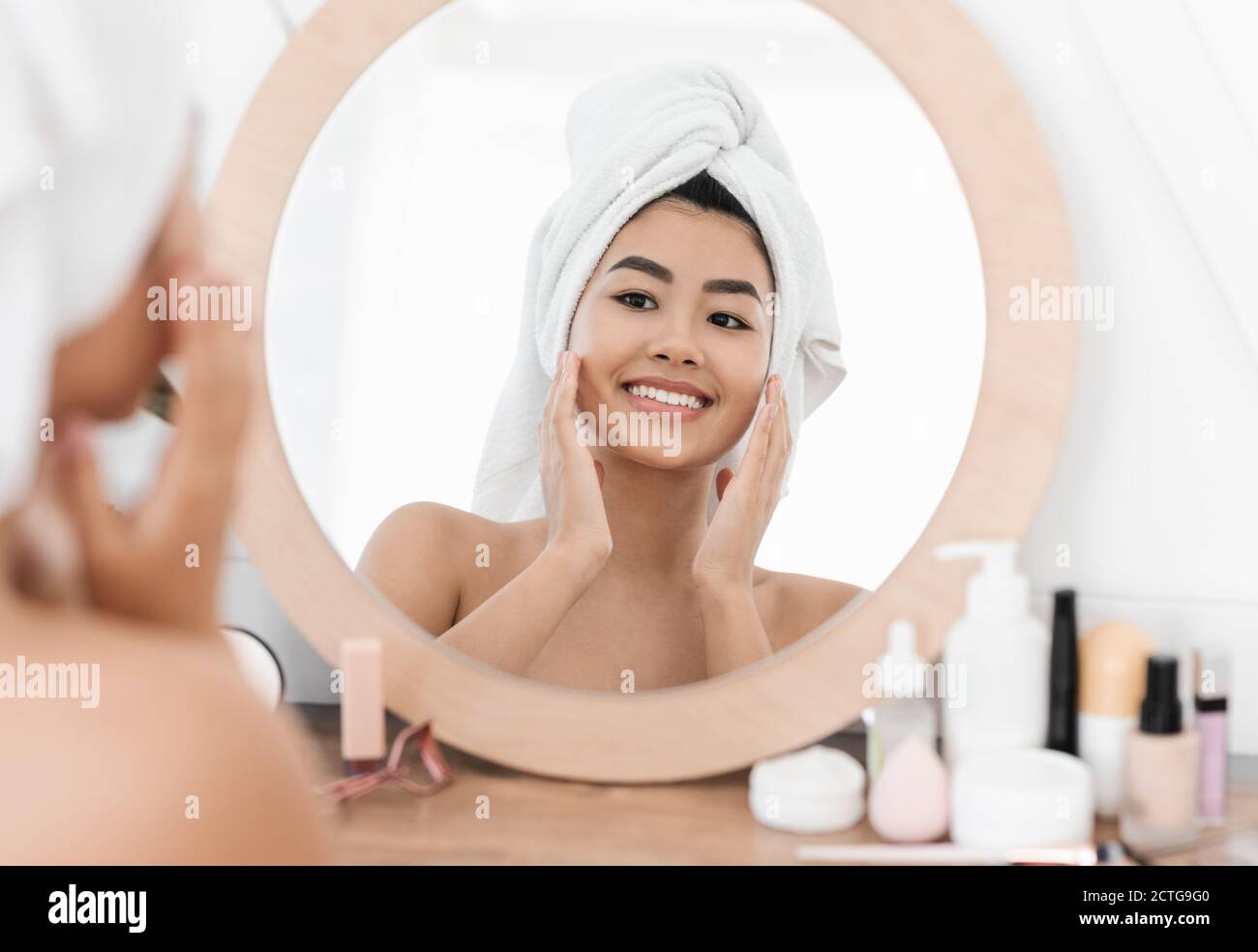 Joyeuse asiatique jeune femme appliquant le produit de beauté Banque D'Images
