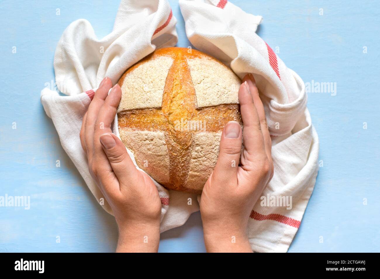 les mains des femmes contiennent le pain de levain fraîchement cuit dans la serviette de Four sur table en bois bleu vue sur le dessus Flat Lay fait maison pâtisserie Banque D'Images