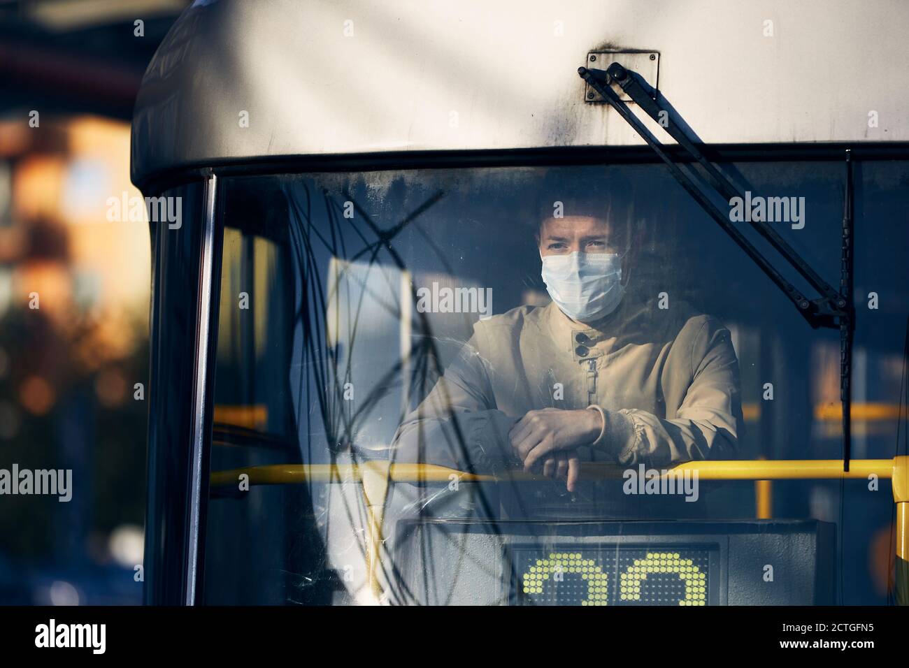 Homme portant un masque et regardant de la fenêtre du tram. Thèmes le transport public dans la nouvelle norme, le coronavirus et la protection personnelle. Banque D'Images