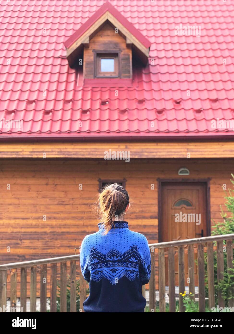 Jeune femme avec queue de cheval en chandail bleu debout devant d'une maison en bois Banque D'Images