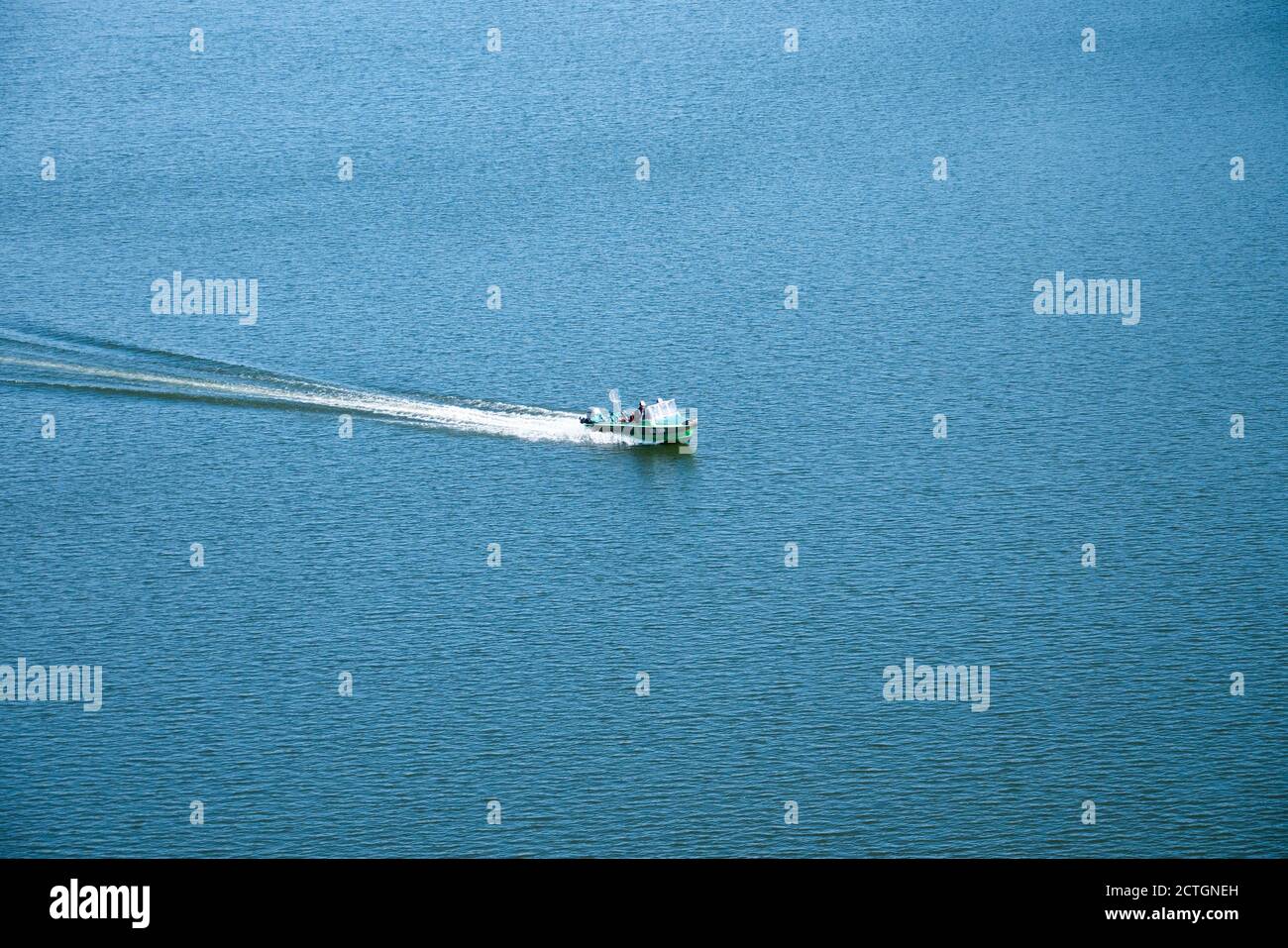 Le bateau à moteur vert se déplace le long de la surface bleue de la mer Banque D'Images