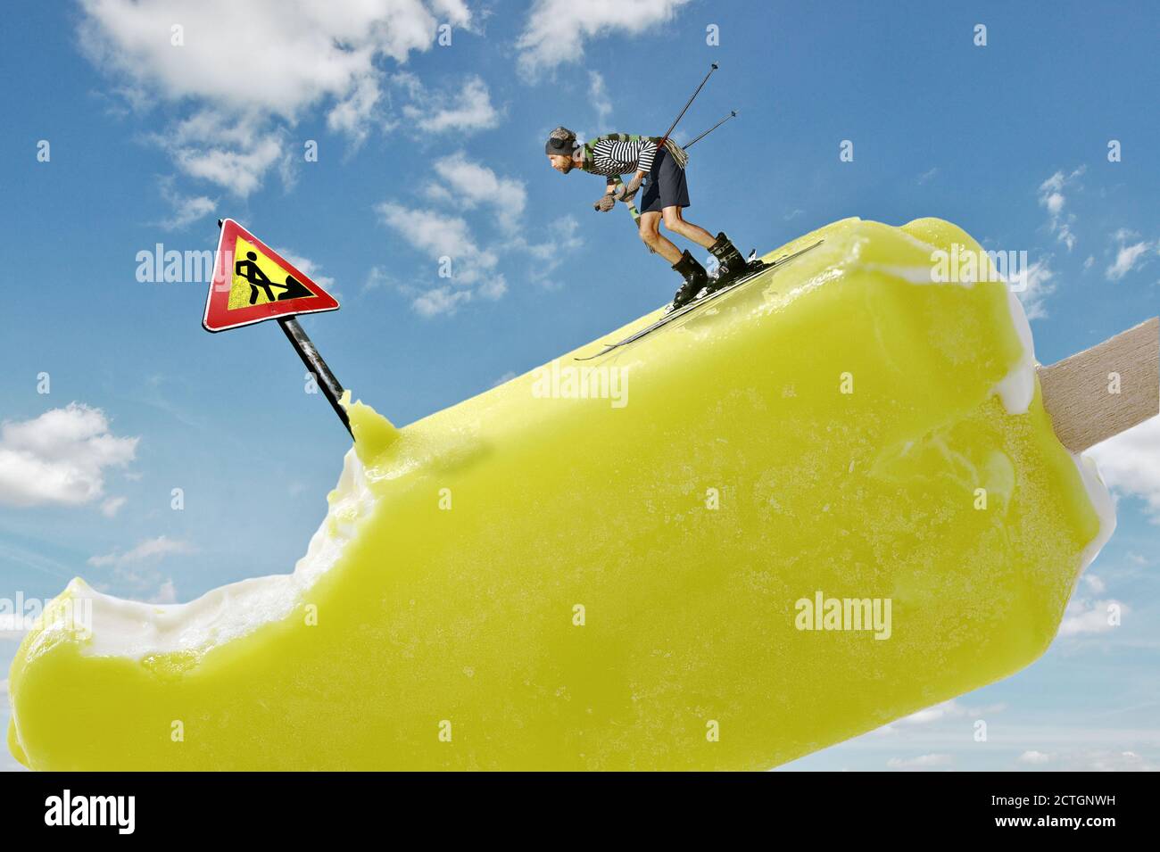 Mini skieur de montagne qui descend une colline de glace avec le signe de la route de danger et de fossé sur fond de ciel bleu ensoleillé, scène conceptuelle des sports d'hiver Banque D'Images