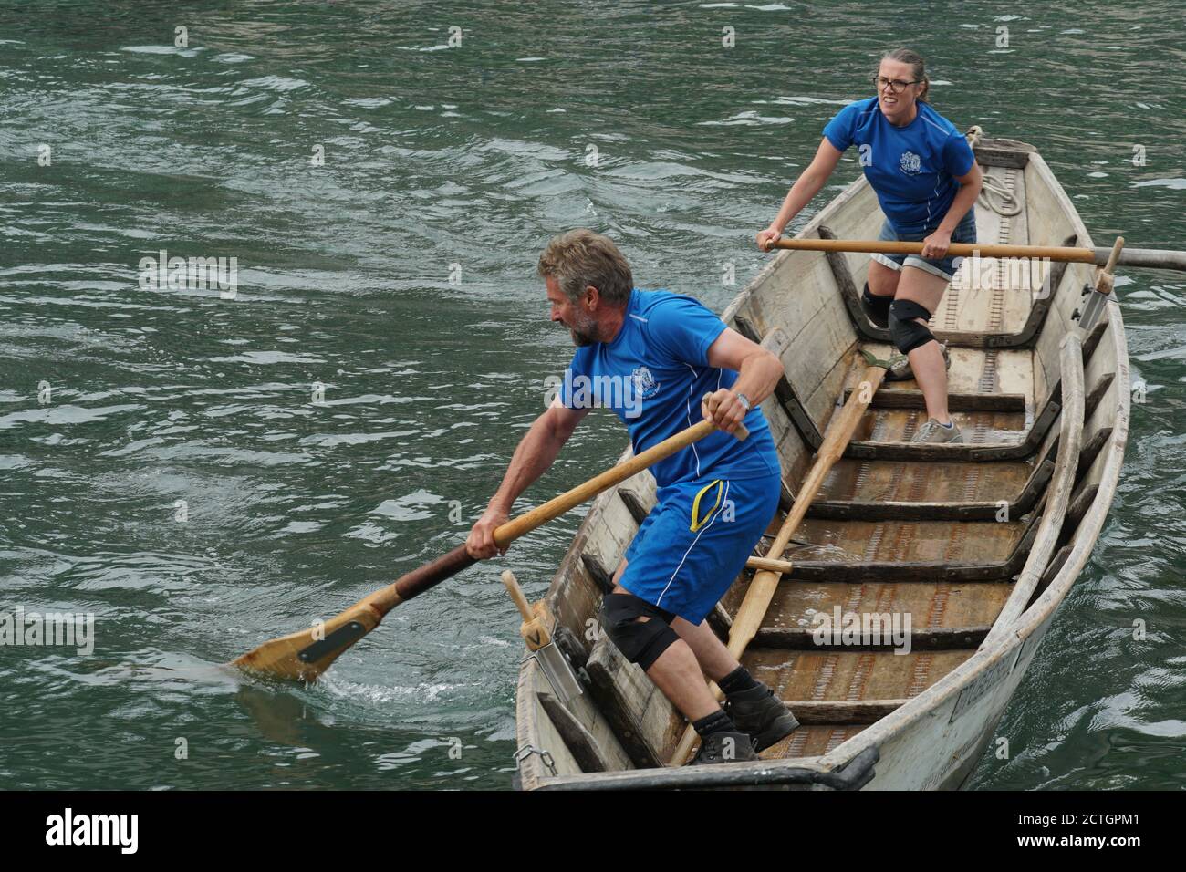 Homme et femme dans un pêcheur suisse traditionnel bateau en bois sur un événement sportif. Ils sont debout et déplacent le navire avec des oars sur la rivière Limmat. Banque D'Images