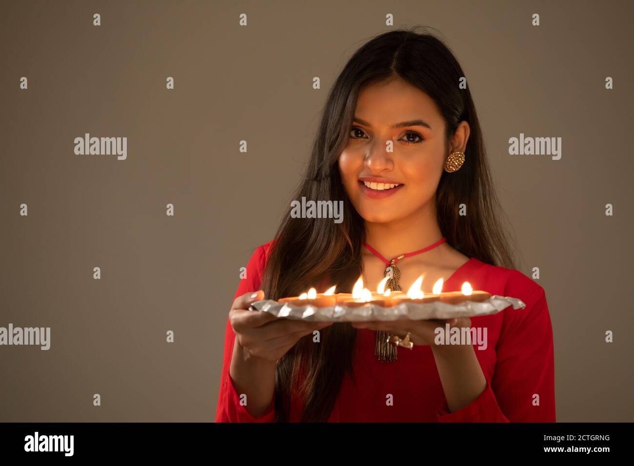 Femme en tenue ethnique tenant une assiette pleine de diyas entre ses mains Banque D'Images