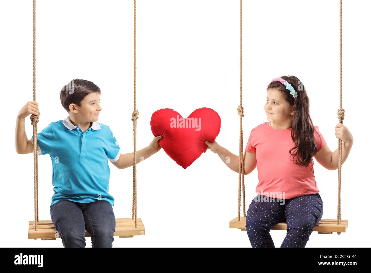 Enfants sur une balançoire tenant un coeur rouge et regardant les uns aux autres isolés sur fond blanc Banque D'Images