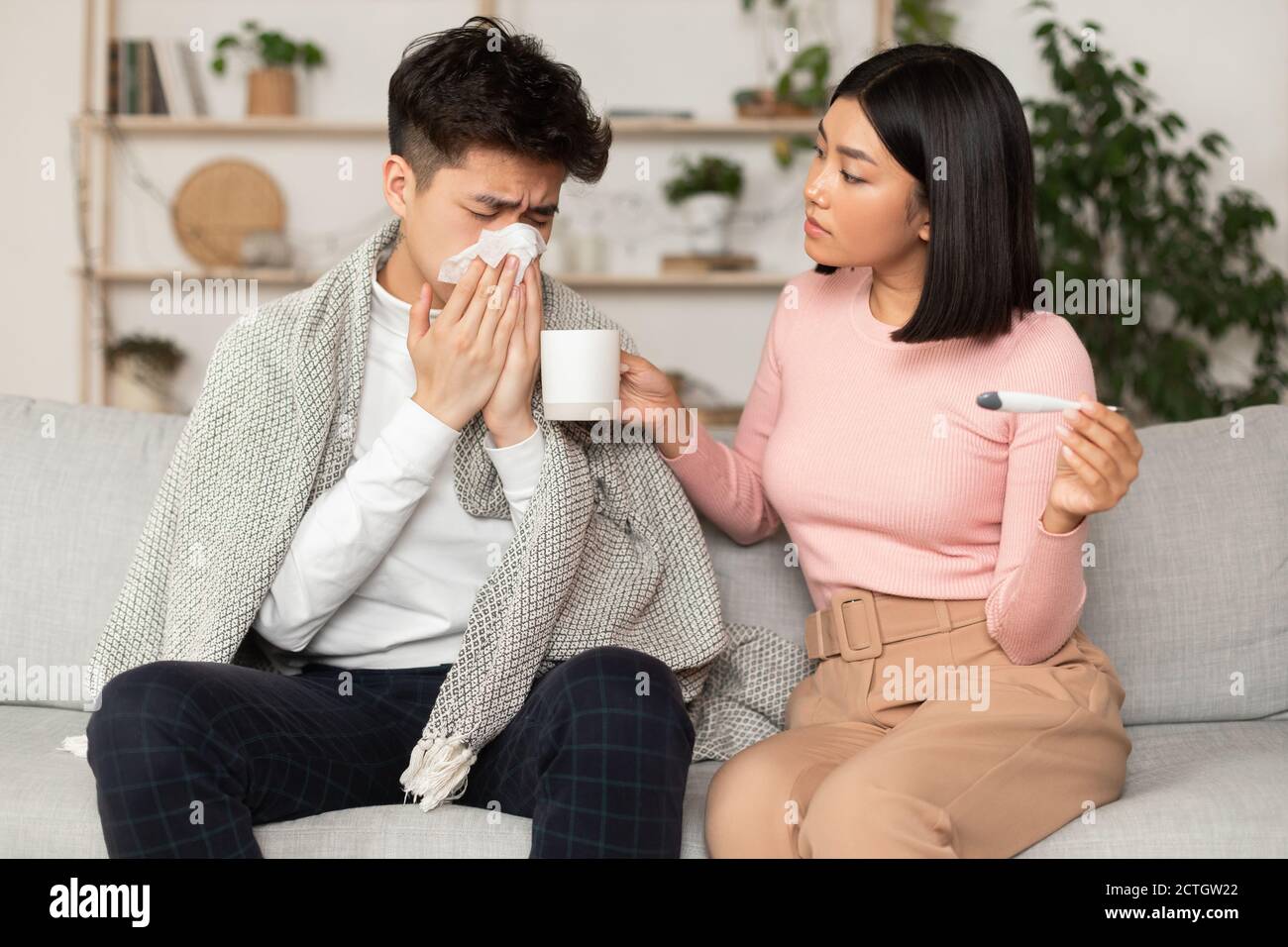 Femme chinoise traitant mari malade donnant des médicaments assis à la maison Banque D'Images
