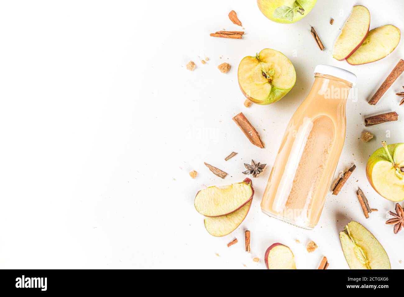 Smoothie aux pommes et aux poires en petite bouteille, avec épices traditionnelles fraîches d'automne, sur fond blanc Banque D'Images