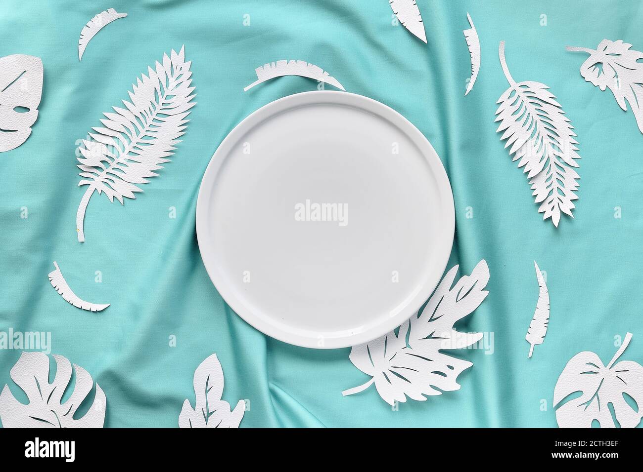 Ai Aqua - couleur tendance de 2021 ans. Vue sur le haut à la mode, feuilles de papier exotiques sur du textile bleu menthe. Banque D'Images