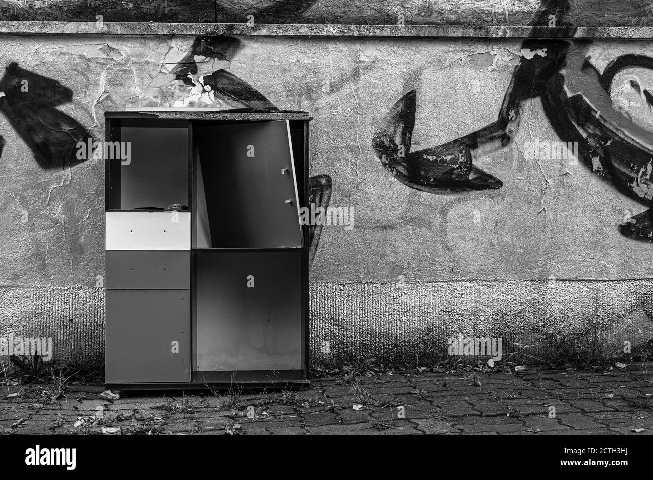 Un vieux placard cassé se trouve devant un mur pulvérisé d'argent, de gros déchets dans la rue, un placard cassé dans la rue Banque D'Images