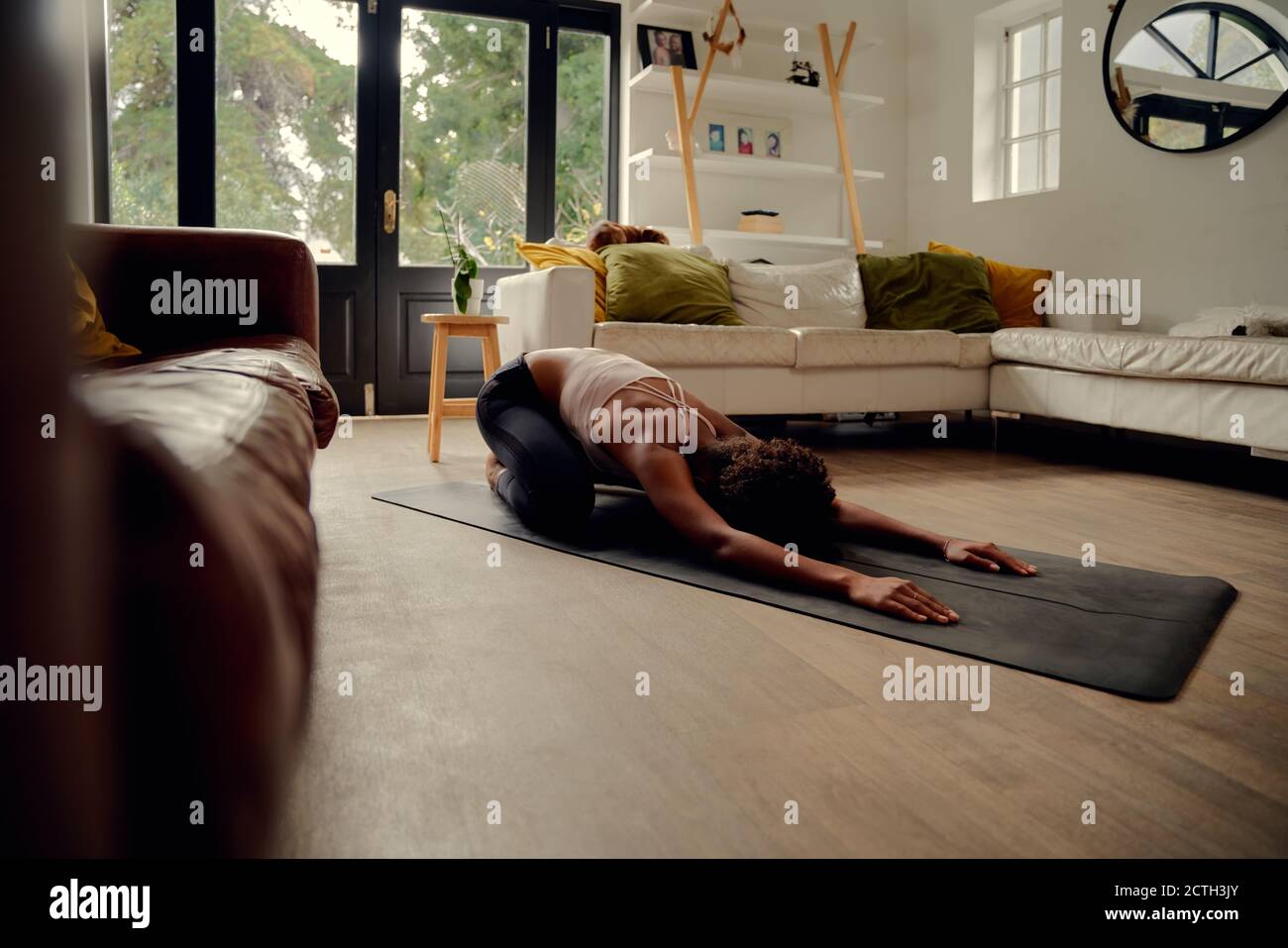 Vue latérale de la jeune femme africaine faisant de l'exercice de forme physique à chez vous sur un tapis de yoga Banque D'Images