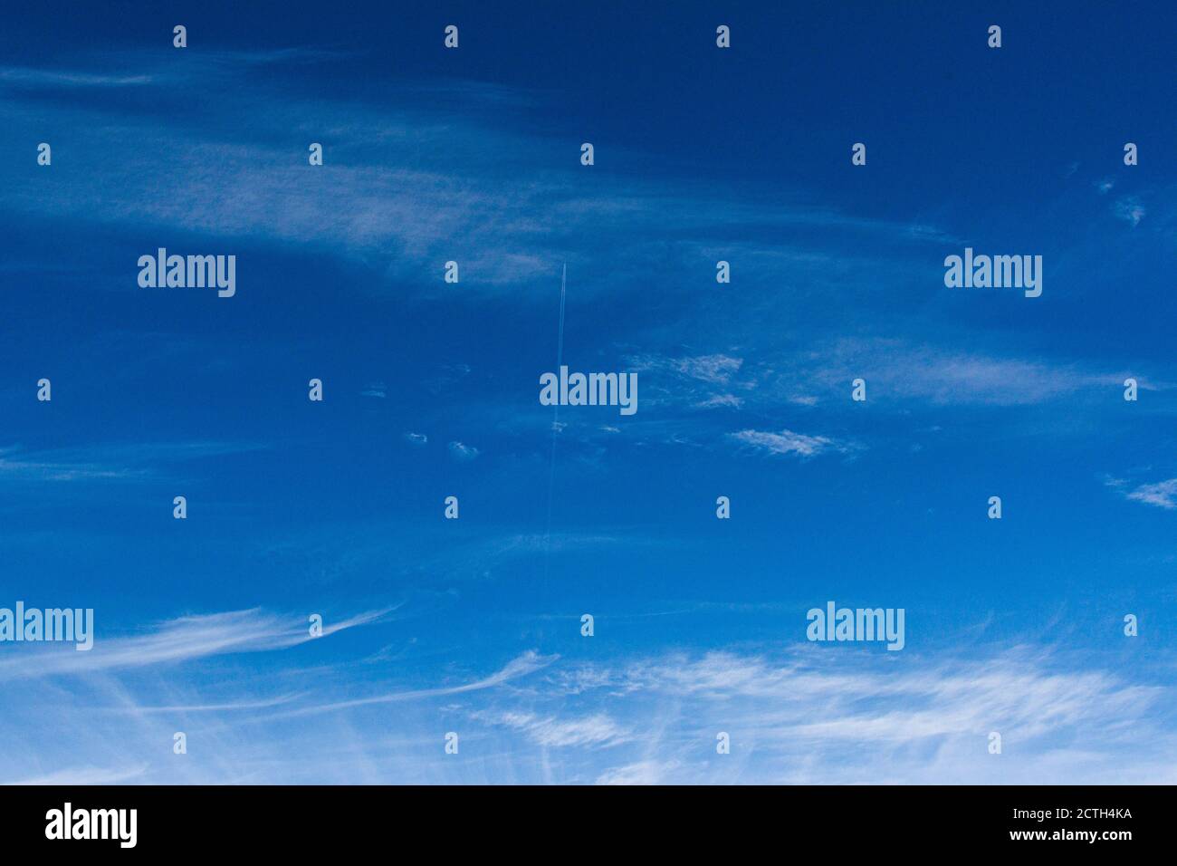 Un seul avion faisant un contrail dans un ciel bleu avec des nuages blancs Banque D'Images