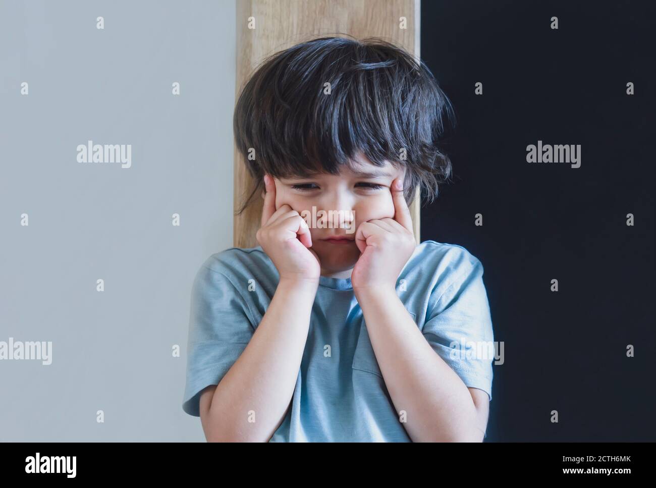 Portrait émotionnel Angry agressif gamin, enfant debout seul avec le visage contrarié ou triste, petit garçon de trouble a couvert son visage avec la main de faire en colère ou ma Banque D'Images