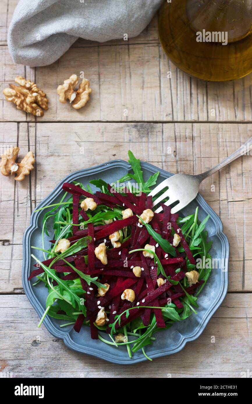 Salade de vitamines de betteraves crues, arugula, noix et huile d'olive sur une table en bois. Style rustique. Banque D'Images