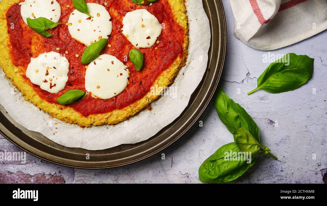 Pizza maison en croûte de chou-fleur recouverte de feuilles de basilic frais Banque D'Images