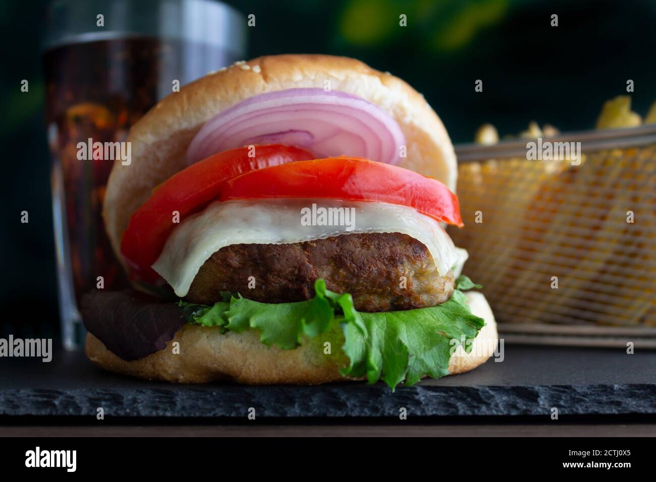Cheeseburger avec frites et Coca-Cola froid sur le bord de l'ardoise , sur fond noir Banque D'Images