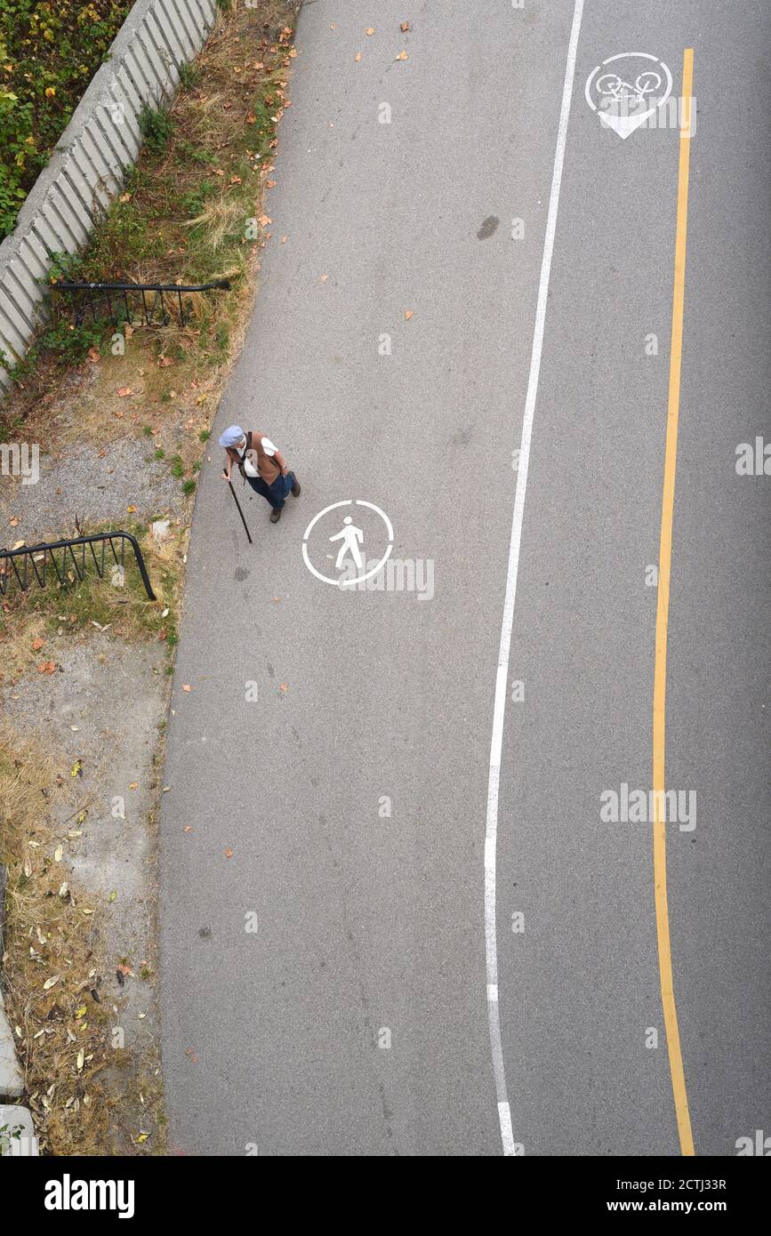 Vue aérienne d'un seul homme avec un bâton de marche à l'aide d'un passage piétonnier marqué à côté d'une piste cyclable à Vancouver, Colombie-Britannique, Canada Banque D'Images