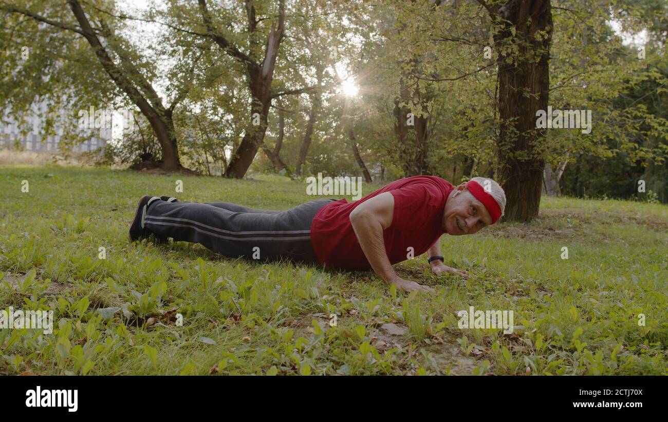 Homme sportif âgé effectuant des exercices de poussée. Entraînement cardio à l'extérieur dans le parc de la ville le matin. Portrait de la forme physique grand-père ancien appréciant le sport et un style de vie sain. Personnes âgées actives Banque D'Images