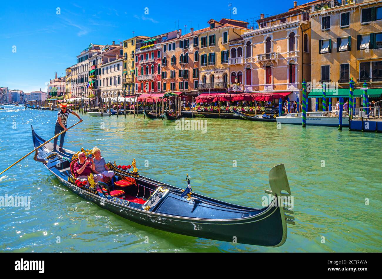 Venise, Italie, 13 septembre 2019 : gondolier et touristes en gondole bateau traditionnel naviguant sur l'eau du Grand Canal avec architecture vénitienne typique bâtiments colorés arrière-plan Banque D'Images