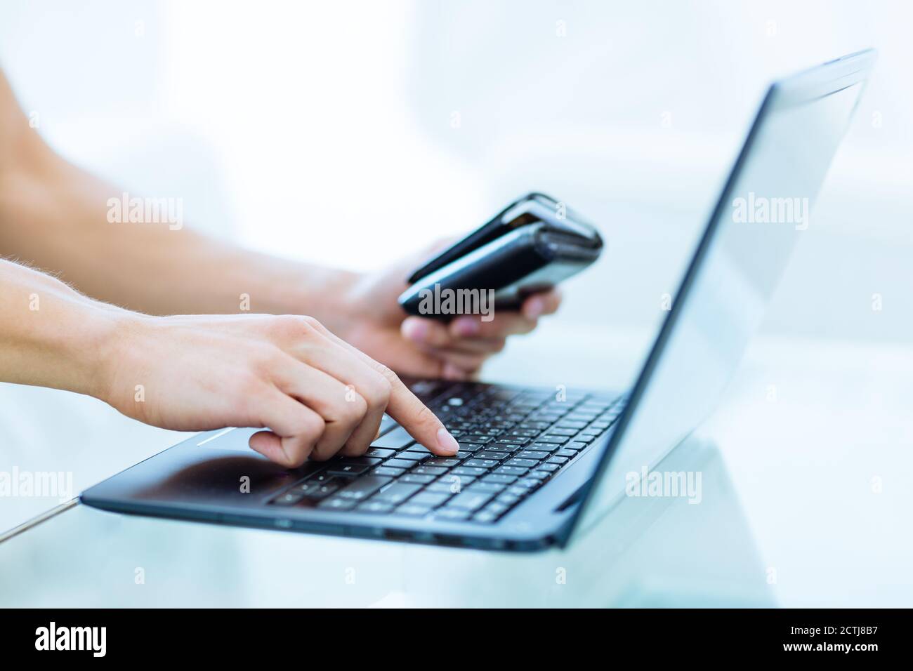 Services bancaires, achats et réservations en ligne. Gros plan de la main d'une personne tenant un portefeuille tout en utilisant un ordinateur portable. Banque D'Images