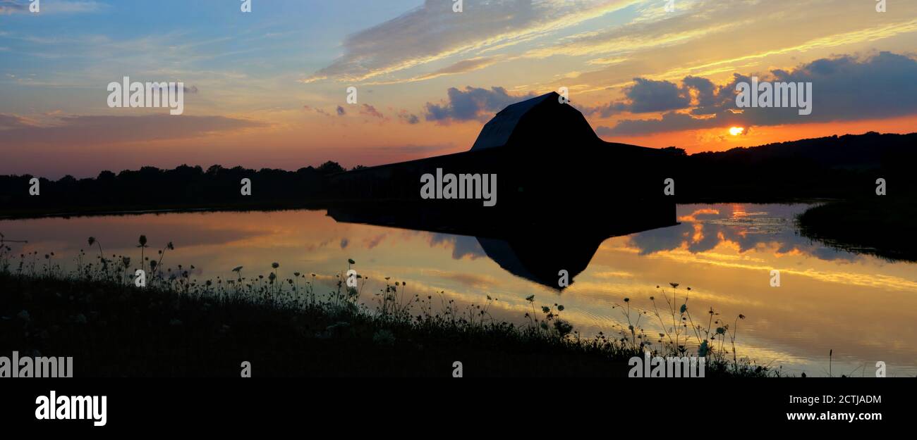 Ancienne Grange et coucher de soleil reflétés dans l'eau Banque D'Images