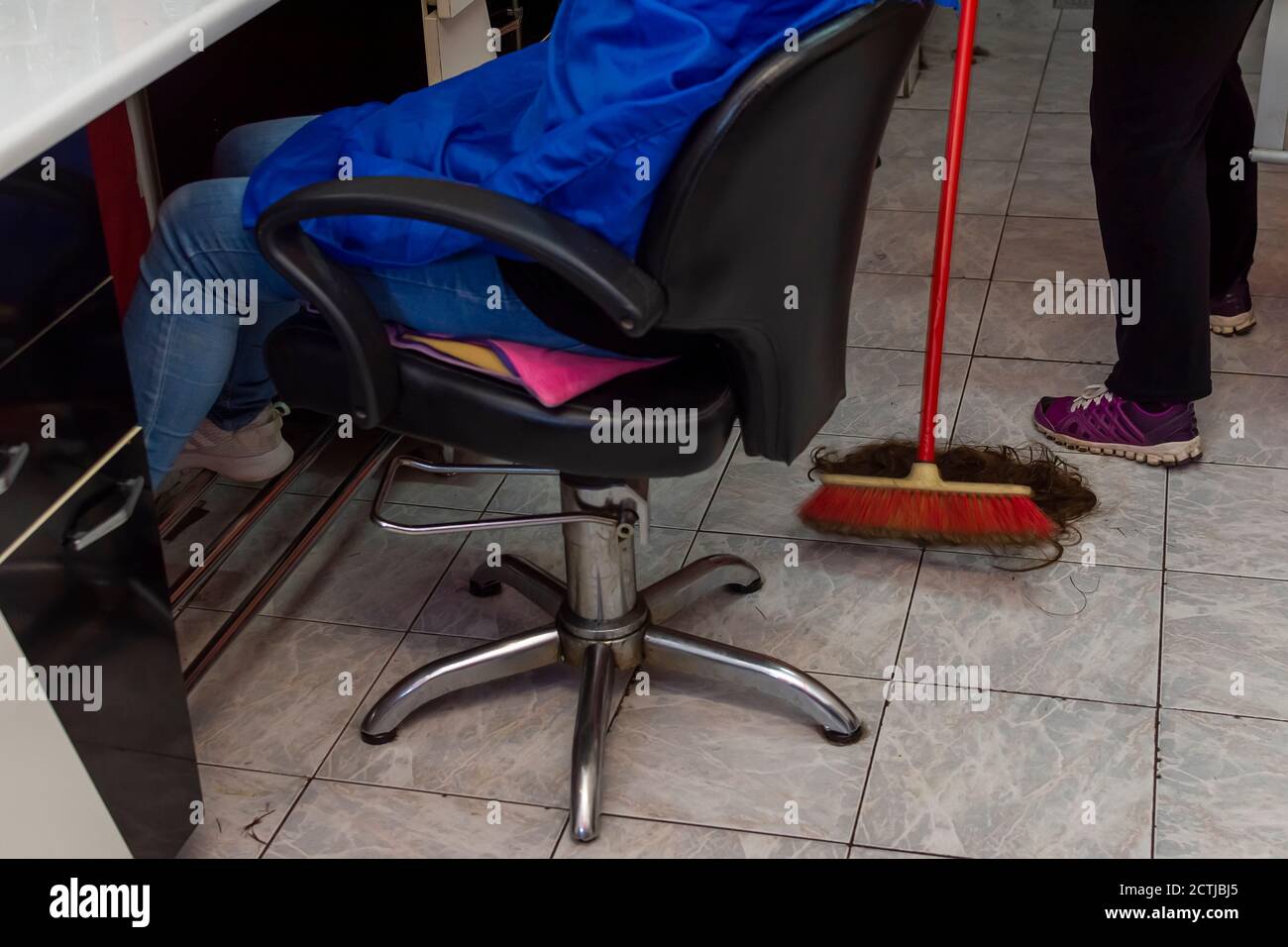 Femme nettoyant le sol des cheveux coupés après le client Banque D'Images