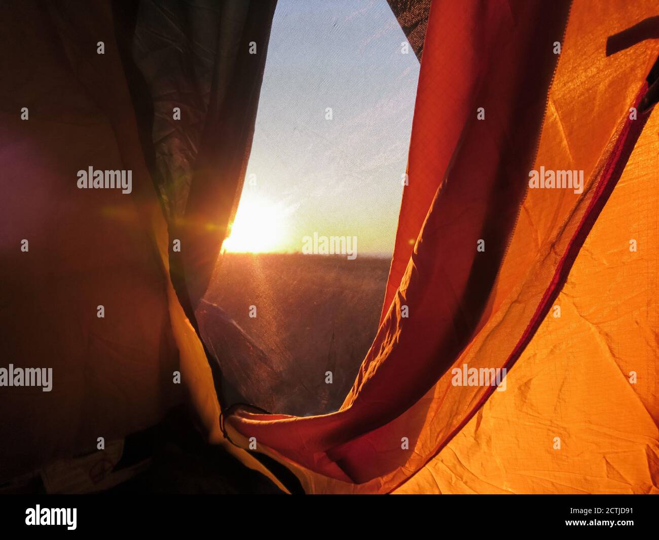 Orange camping touristique tente fenêtre donnant sur le soleil au lever du soleil. Loisirs dans la nature romantique Banque D'Images