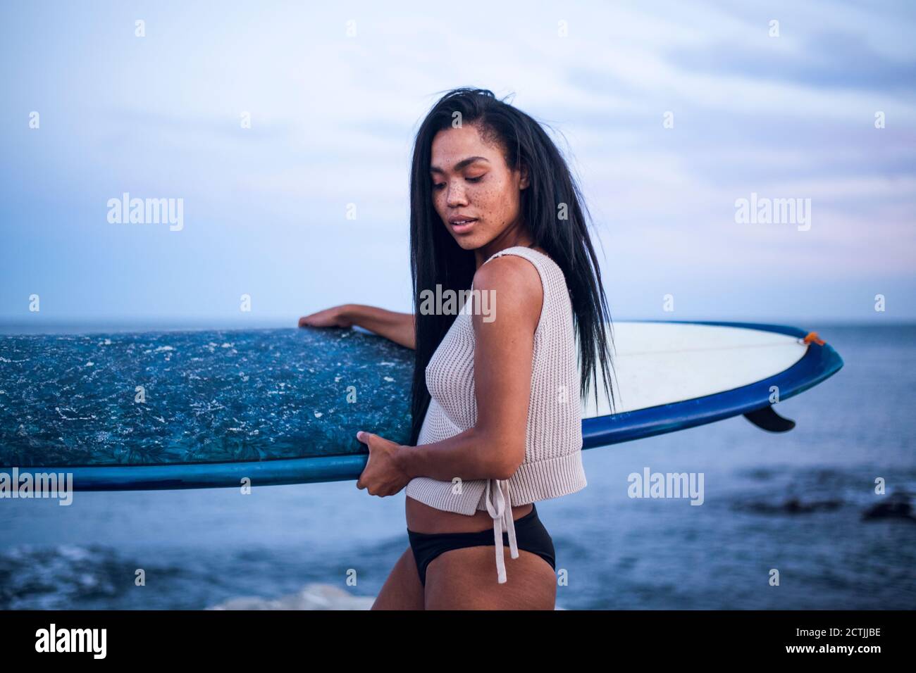 Portrait de style de vie de femme noire multiraciale au bord de l'océan avec planche de surf Banque D'Images