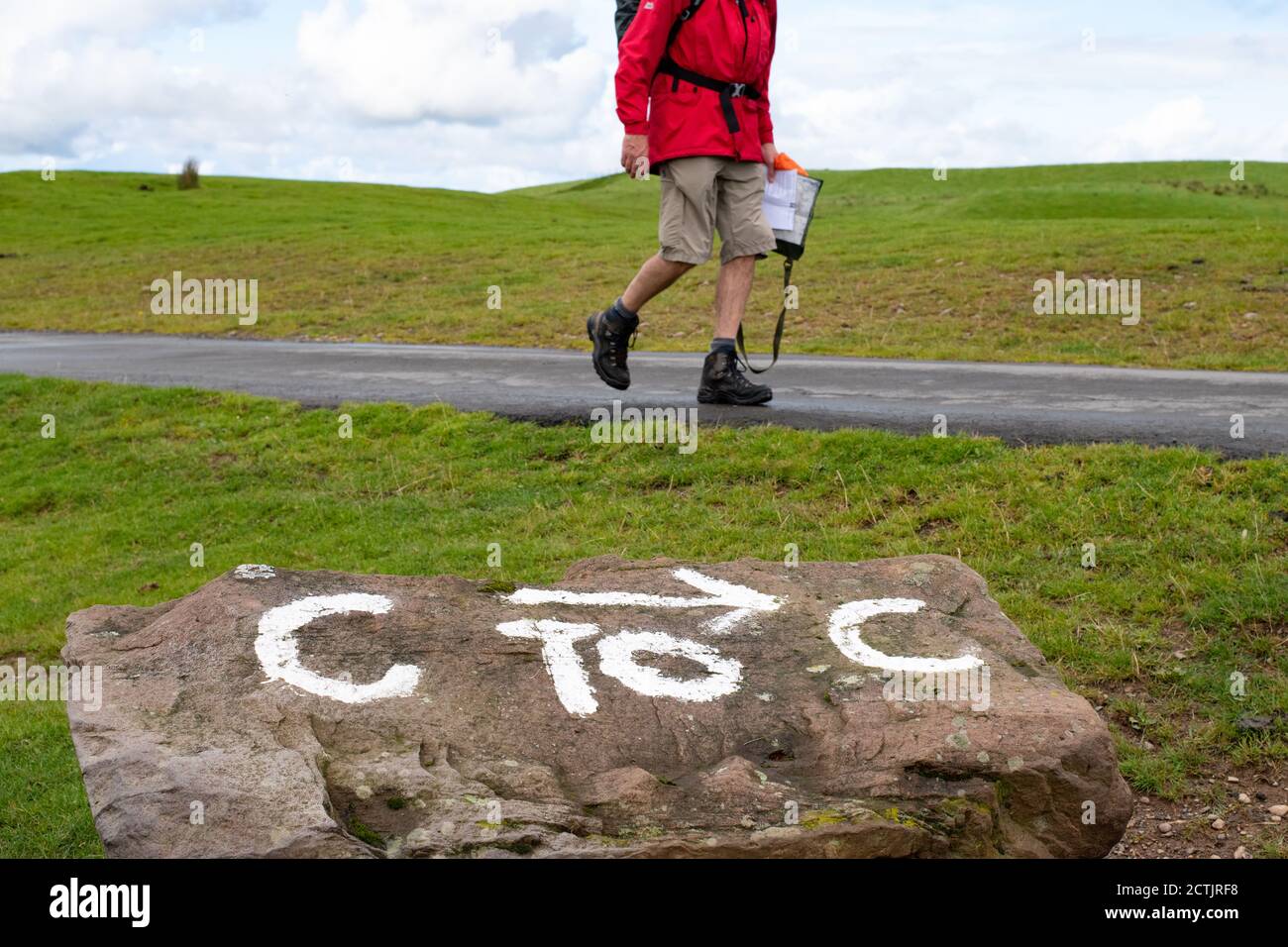 walker sur Wainwright's Coast to Coast Walk en passant le panneau peint à la main C to C à l'approche du pont Ennerdale, Lake District, Angleterre, Royaume-Uni Banque D'Images