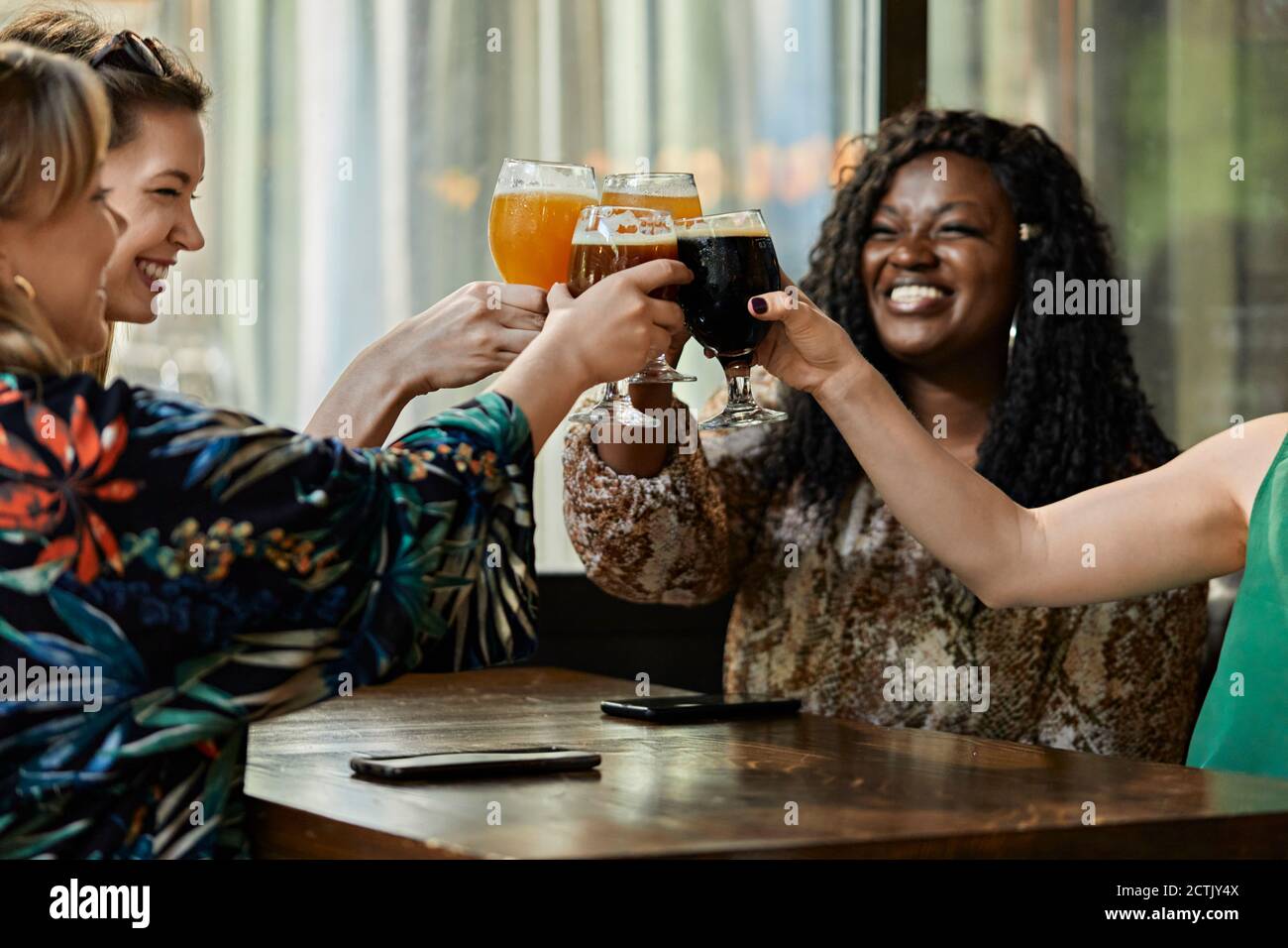 Des amies joyeuses qui se contentent de prendre des verres à bière artisanaux dans un pub Banque D'Images